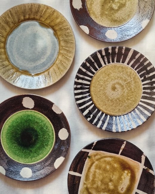 Flat lay of glazed ceramic plates in warm tones, from @obsidianandflame