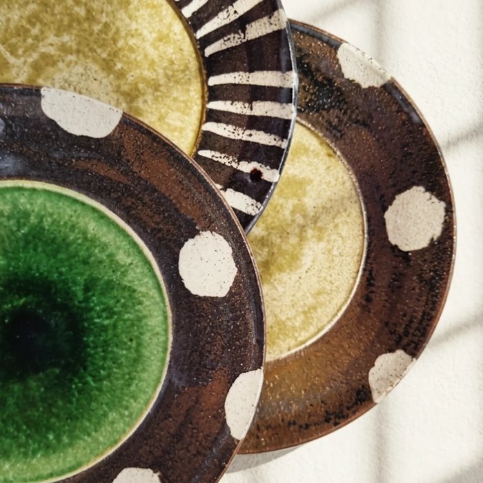 Detail of overlapping striped and dotted ceramic plate rims, from @obsidianandflame