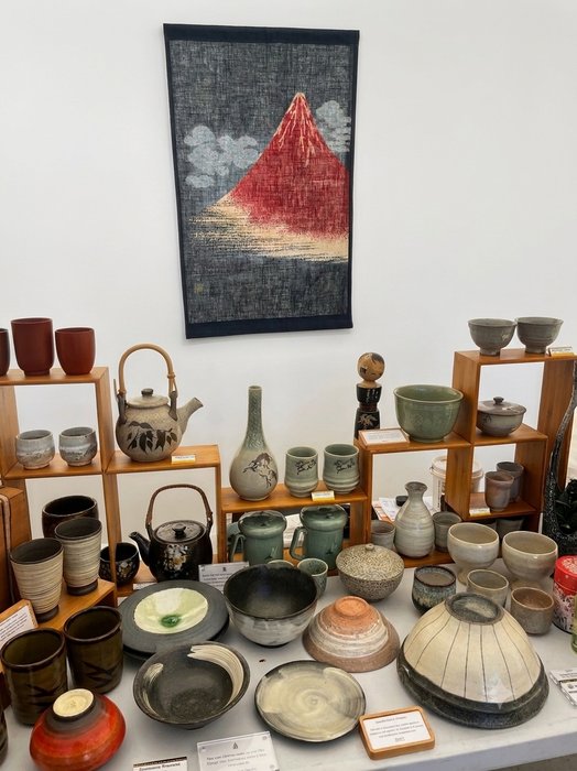 Ceramic cups, teapots and bowls displayed on wooden shelving