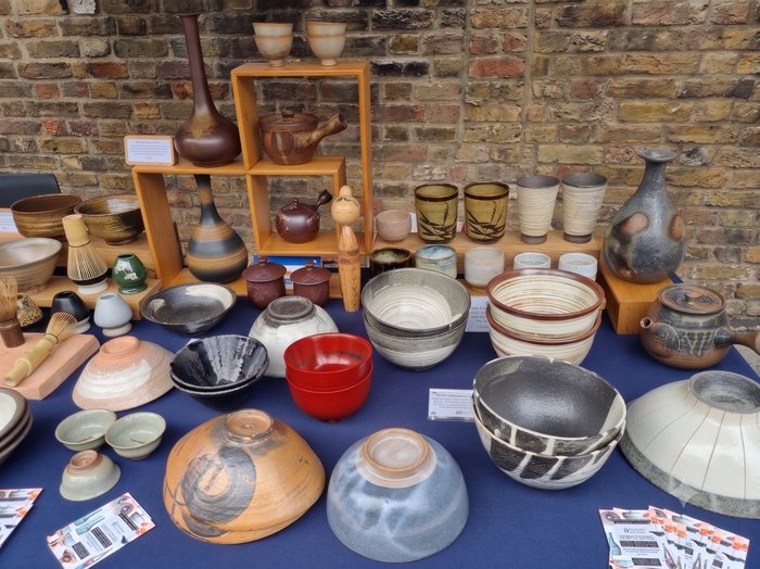 Ceramics displayed on a market stall against a brick wall